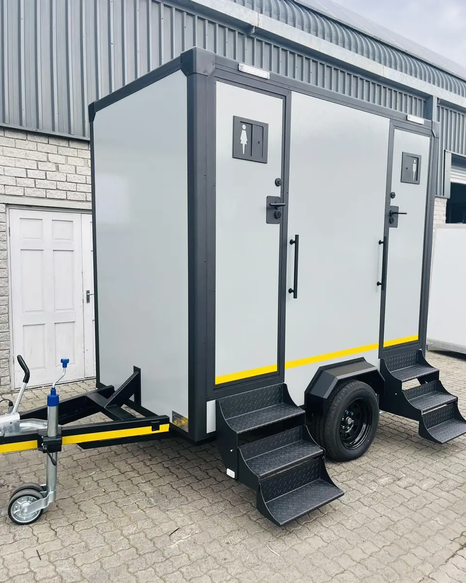 Two-stall restroom trailer with folding steps parked on pavers
